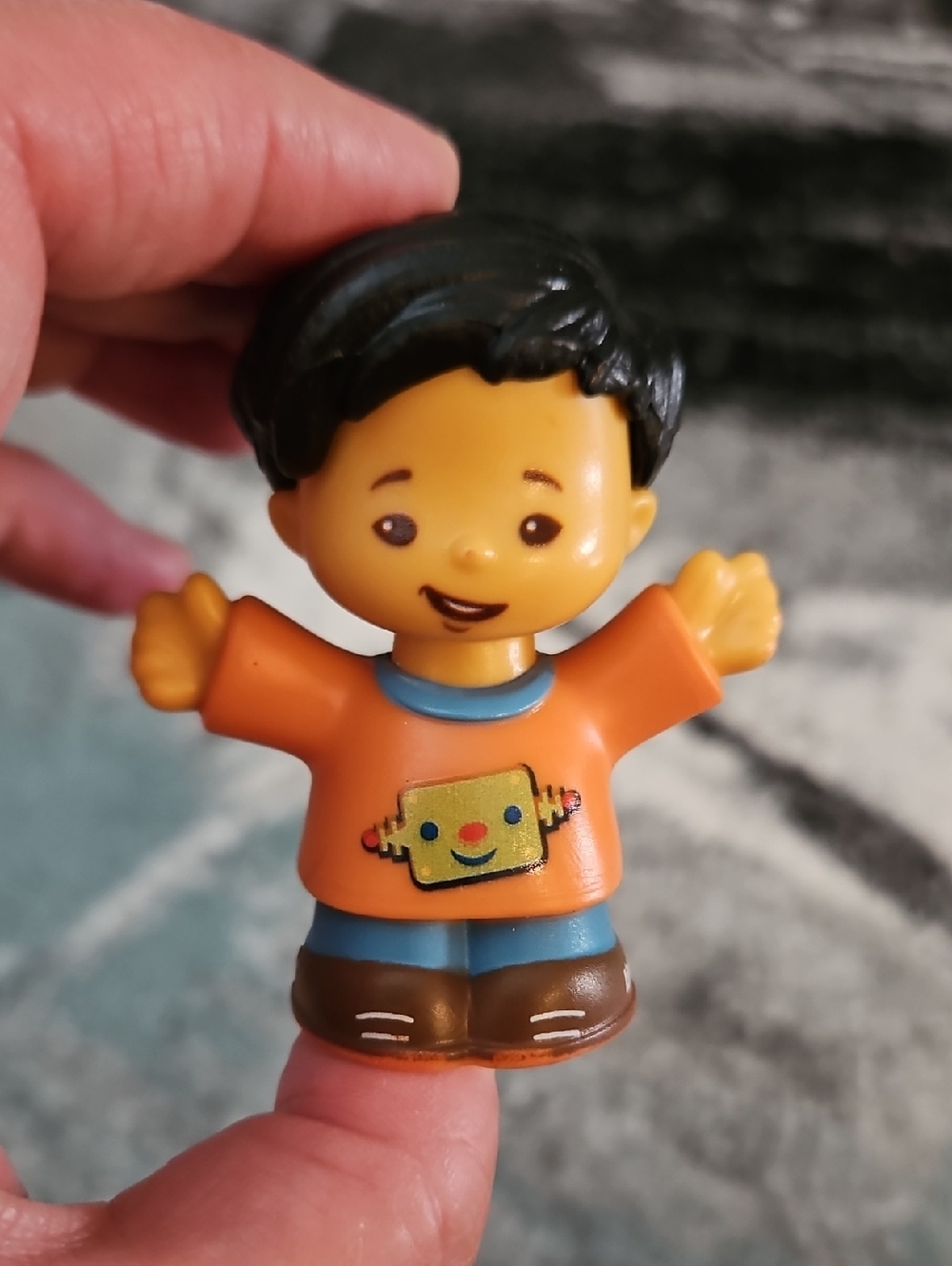 Fisher-Price Little People Koby figure wearing an orange shirt with a robot grap